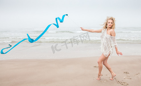 跳舞丝带摄影照片_体操女子在沙滩上用丝带跳舞