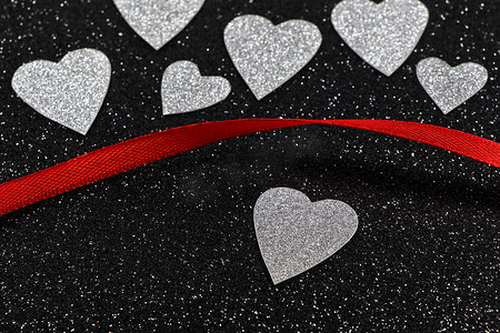 纹理情人节活动摄影照片_银色的心和带纹理的黑色红丝带