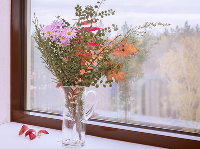 窗台上有一束秋天的花朵和叶子。