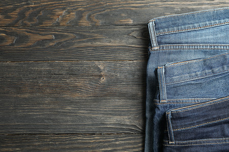 衣柜木质摄影照片_不同的牛仔裤折叠在木质背景上，文字空间