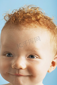 蓝色背景中噘起嘴唇的红发可爱婴儿的特写