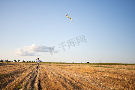 一个男孩带着风筝跑过田野。