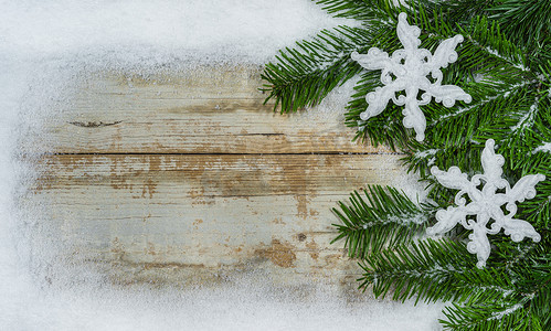 圣诞装饰雪花摄影照片_圣诞装饰，有杉树枝、白色雪花饰物和木头上的雪边，复制空间