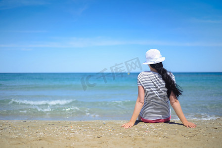 年轻女子坐在沙滩上，望着大海
