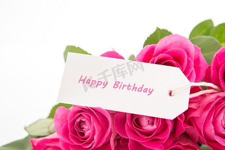 一束美丽的粉红玫瑰的特写，白色背景上有一张生日快乐卡