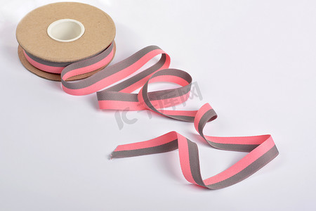 粉色和灰色的棉质丝带，卷绕在线轴上的纺织品。