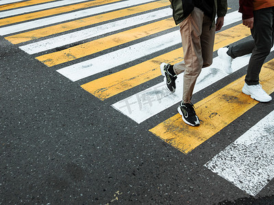 交通马路摄影照片_两个年轻人在人行横道处过马路。