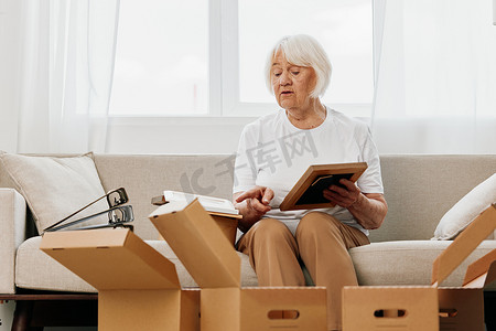 老妇人坐在家里的沙发上，手里拿着箱子。