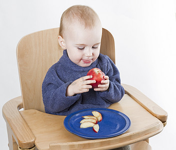 小孩坐在高脚椅上吃桃子