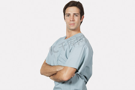 穿手术服的医生摄影照片_灰色背景下身穿外科手术服的自信年轻人的画像