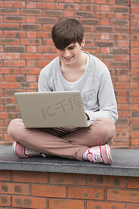 男人盘腿坐着，在外面使用笔记本电脑