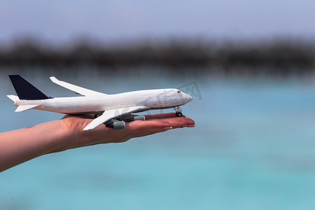 小飞机旅游摄影照片_在绿松石海背景的小的白色玩具飞机