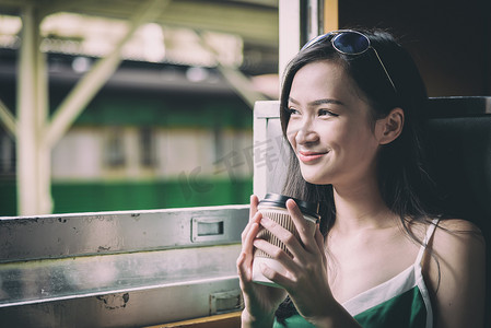 亚洲女旅客在火车上喝咖啡，开心