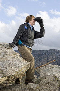 快乐的高级女徒步者用双筒望远镜在山中徒步旅行