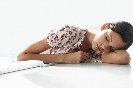 疲惫的年轻女商人睡在办公桌前
