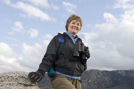 用双筒望远镜在山中徒步旅行的快乐高级女性肖像