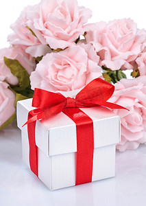 粉红色的花朵和礼盒，上面有红丝带和白色 ba 上的蝴蝶结