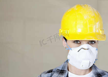 彩色背景下戴防尘面具和安全帽的女工肖像
