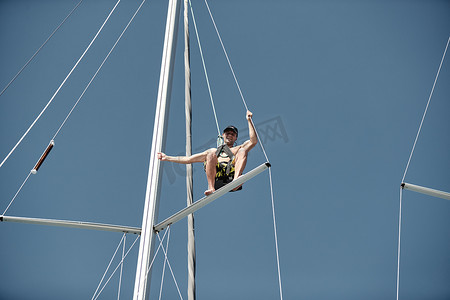 海上帆船运动摄影照片_克罗地亚，斯普利特，2019 年 9 月 15 日：桅杆顶部的水手成本，背景为蓝天的帆船赛的参与者，人们为即将到来的比赛做准备，船长