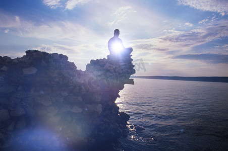 海滩2024摄影照片_坐在岩石上的人在海边沉思的全长视图