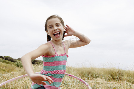 欢快的小女孩在田野里呼啦圈的画像