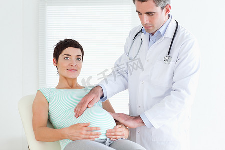 腹诊摄影照片_听诊一名孕妇的肚子的男医生