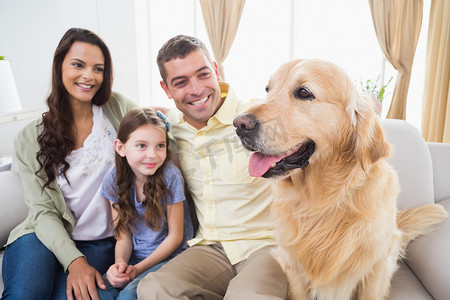 一家人和金毛猎犬坐在沙发上
