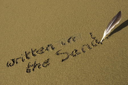字金色沙子摄影照片_用羽毛笔写在沙子上