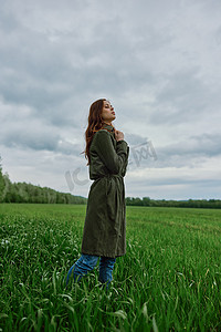 春天雨天，一位身穿深色外套的美女站在绿地里