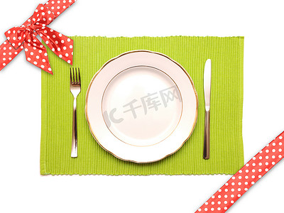 “绿色餐巾纸上的刀、叉和白盘子”