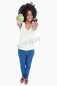 微笑的年轻女人一手拿着苹果，一手拿着松饼