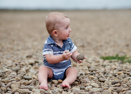 小男孩海边摄影照片_海边玩石头的小男孩