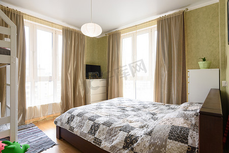 张大千泼墨摄影照片_一间明亮的卧室的内部有一张大双人床和两个大彩色玻璃窗