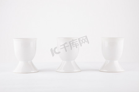 三件物品摄影照片_白色背景中并排的三个空蛋杯