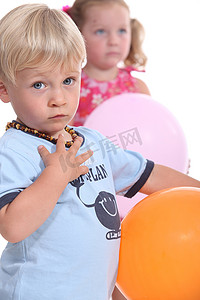 戴着琥珀牙项链的小男孩和他的朋友玩气球
