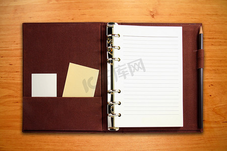 中小学管理摄影照片_棕色帆布活页夹笔记本，带空白卡片和铅笔在木头上