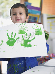 儿童展示摄影照片_小男孩在艺术课上展示他的手指画的肖像