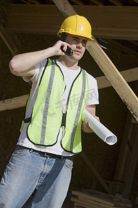 有蓝图的体力劳动者在建筑工地使用手机
