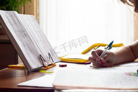 孩子的手在做作业时在笔记本上写字，特写