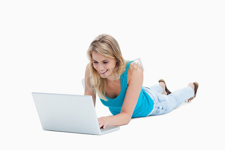 一名年轻女子躺在地板上，手里拿着笔记本电脑