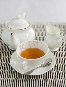 小茶壶摄影照片_一杯带小牛奶罐和茶壶的茶
