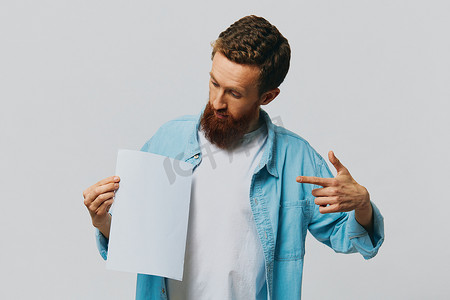 灰色背景中一位成年男性的肖像，手里拿着一张白纸，供您设计和文字、布局、复制空间、文字空间、指点