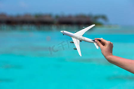 小飞机旅游摄影照片_在绿松石海背景的小的白色玩具飞机