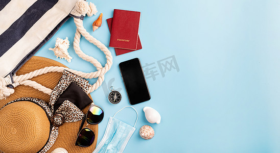 蓝色背景中带夏帽、智能手机、护照、太阳镜和指南针的平躺式旅行物品