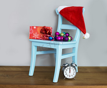 圣诞节绿色帽子摄影照片_椅子上的圣诞老人帽子和礼物