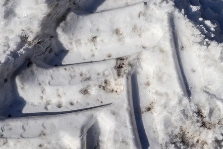 近距离观察积雪覆盖的街道上的轮胎痕迹。