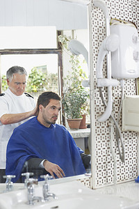 高级理发师在理发店为男士理发