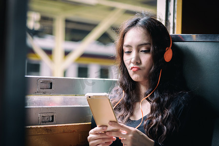 亚洲女性旅行者用电话和橙色 h 听音乐