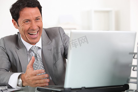 男人歇斯底里地对着他的笔记本电脑大笑