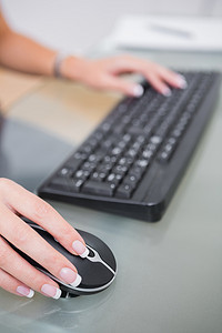 在办公桌上使用电脑鼠标和键盘的手